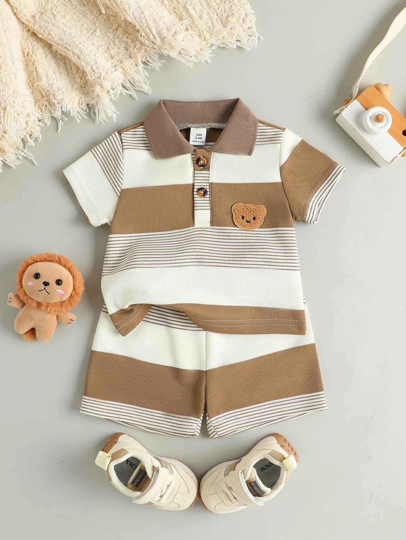 Ensemble bébé polo et short camel présenté à plat avec accessoires