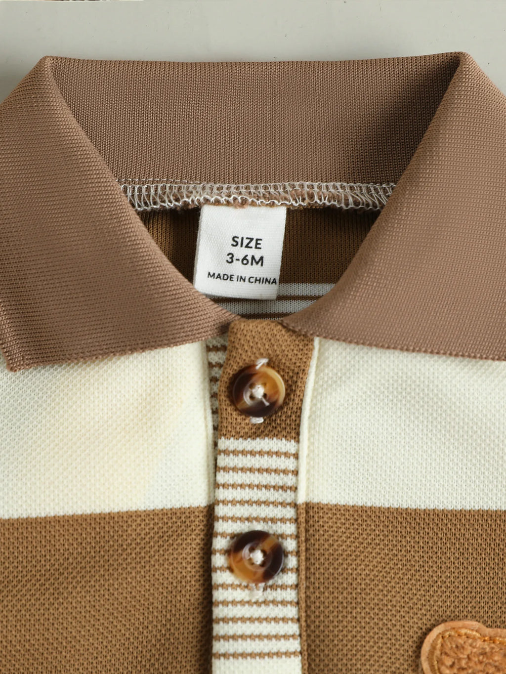 Détail du col à boutons du polo bébé rayé camel
